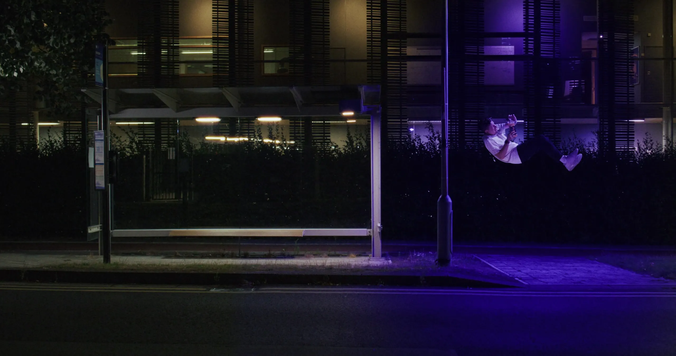 A purple light glows over the empty bus shelter at night