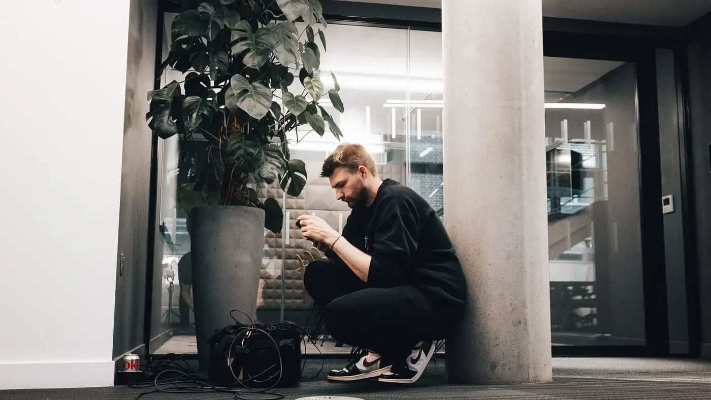 Liam Togher crouches by a glass wall, setting up sound