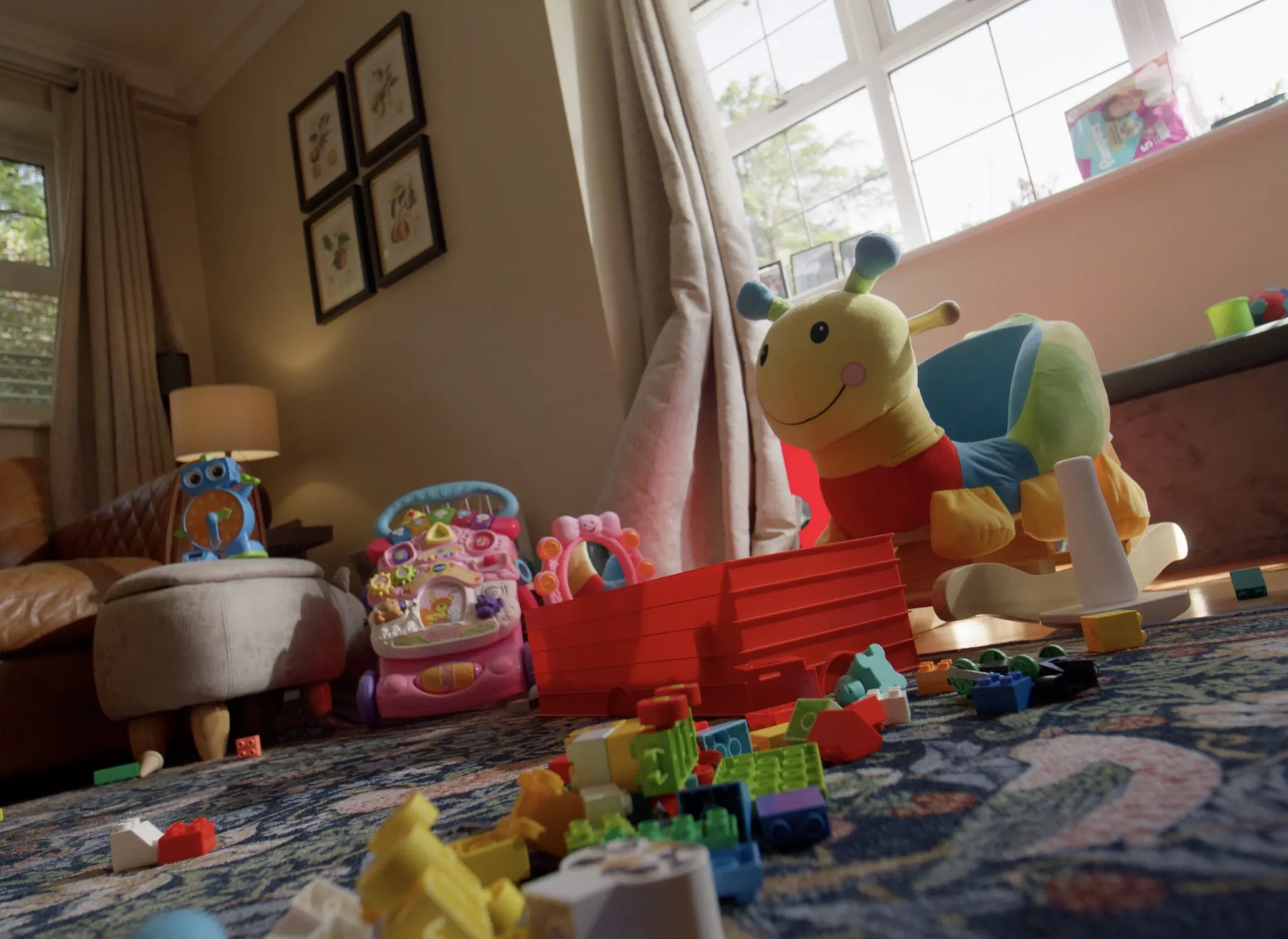 A low view across toys, building blocks and a rocking caterpillar on the living room floor