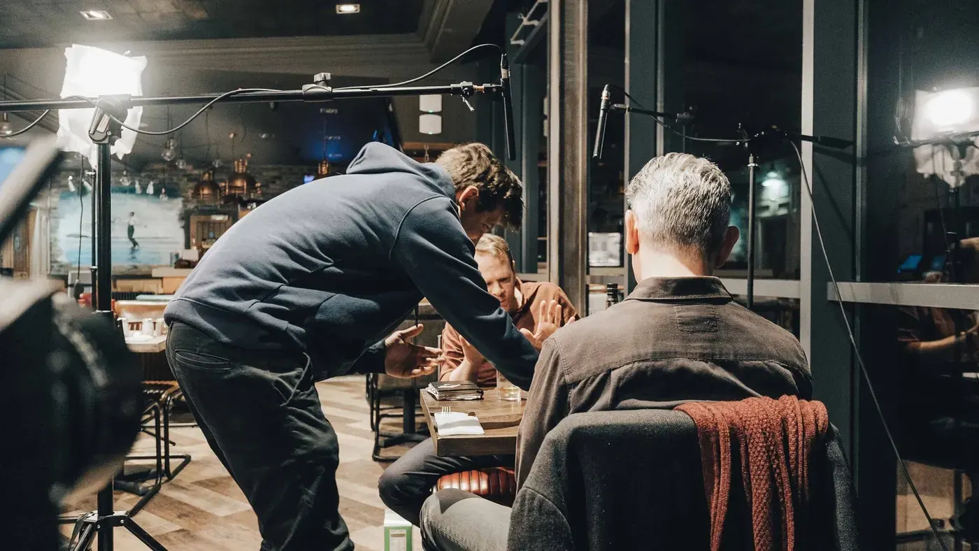Mark G Smith leans in to talk to Toby Williams and David Mills at the table