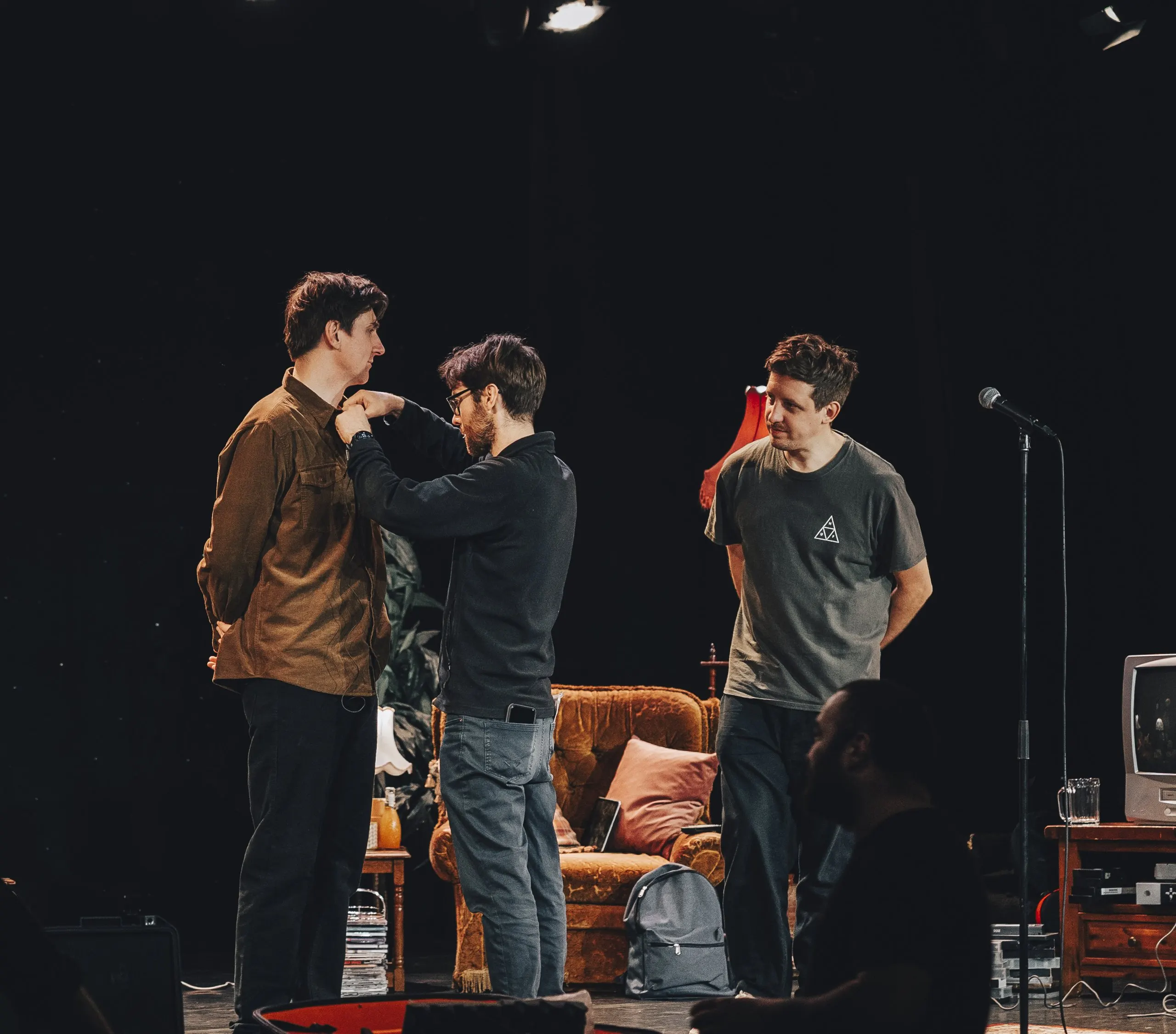 Sean McLoughlin being fitted with a microphone by Sean Plunkett, with Mark G Smith on stage